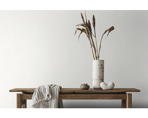 Arrangement décoratif avec banc, vase, graminées ornementales et textiles à l''intérieur.
