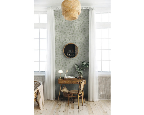 Intérieur décoratif avec une table en bois, un miroir rond et un papier peint à motifs de feuilles dans une pièce lumineuse