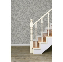 Scène avec un escalier, un mur avec du papier peint à motifs de feuilles et un plancher en bois