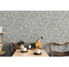 Papier peint gris à feuilles derrière une table en bois dans une pièce lumineuse.
