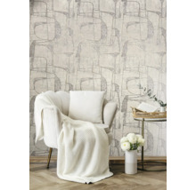 Salon lumineux avec fauteuil, couverture, coussin, table d''appoint, fleurs et papier peint à motifs