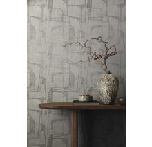Un mur avec du papier peint graphique, décoré d''un vase en bois sur une table.