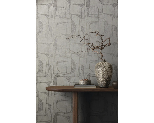 Un mur avec du papier peint graphique, décoré d''un vase en bois sur une table.
