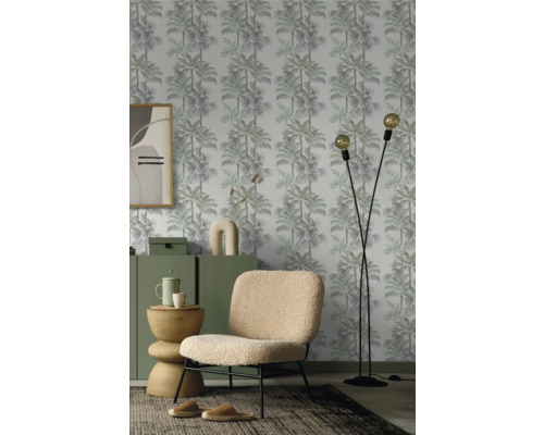 Salon avec papier peint à motifs de palmiers, fauteuil et lampadaire.