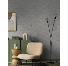 Wohnzimmer mit einem Sessel, Stehlampe und einer Kommode vor einer Wand mit einem geometrischen Muster.