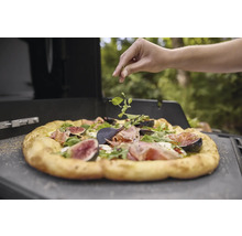 Une pizza aux figues et à la roquette est garnie d''herbes fraîches.