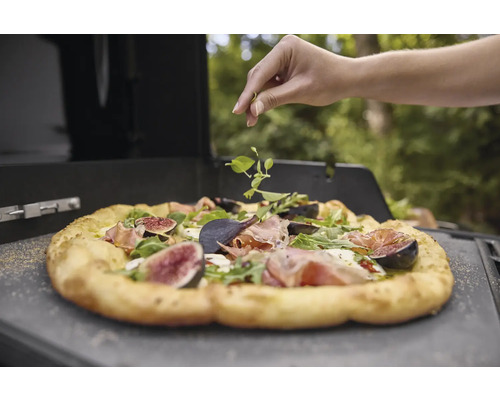 Une pizza aux figues et à la roquette est garnie d''herbes fraîches.