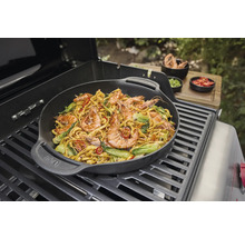 Plat au wok avec des crevettes et des légumes préparé sur un barbecue.
