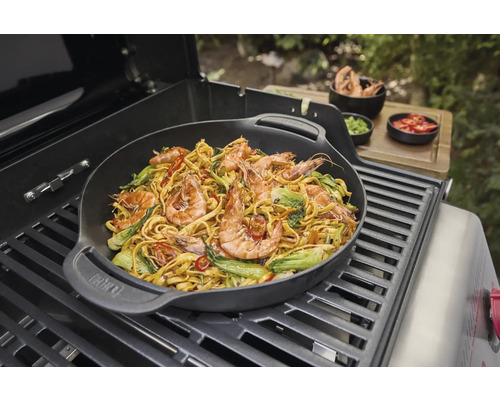 Plat au wok avec des crevettes et des légumes préparé sur un barbecue.
