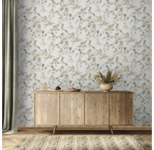 Szene mit einem hölzernen Sideboard vor einer floralen Tapete und einem Teppich.