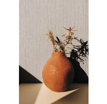 Vase décorative avec fleurs séchées devant un papier peint structuré