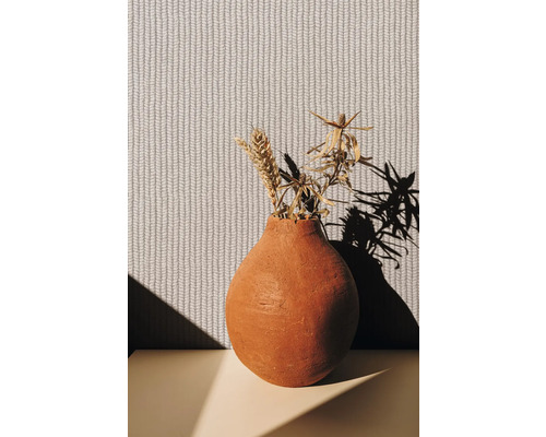 Vase décorative avec fleurs séchées devant un papier peint structuré