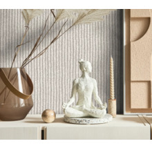 Espace décoratif avec papier peint à motif tricoté, une statue de Bouddha, un vase avec des fleurs séchées et une bougie.