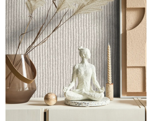 Espace décoratif avec papier peint à motif tricoté, une statue de Bouddha, un vase avec des fleurs séchées et une bougie.