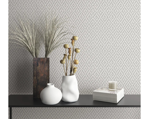 Dekoratives Interieur mit gemusterter Tapete, Vasen, Dekoration und Kerze auf einer schwarzen Oberfläche.