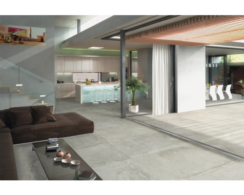 Heller Wohnraum mit Bodenfliesen in Betonoptik, Sofa und offener Küche