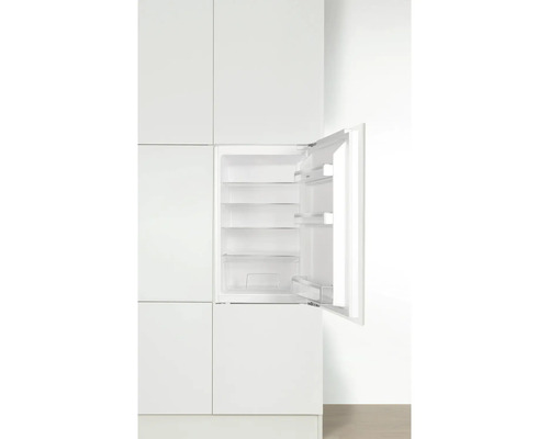 Réfrigérateur intégré avec porte ouverte dans une cuisine blanche.