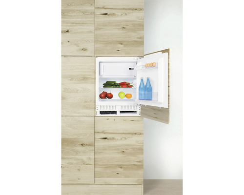 Réfrigérateur intégré aspect bois avec porte ouverte, rempli de produits alimentaires.