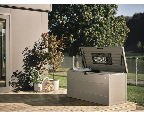 Geöffnete Aufbewahrungsbox auf einer Holzterrasse mit Pflanzen im Hintergrund