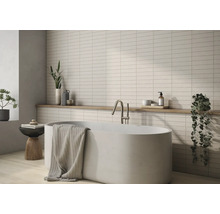 Salle de bains avec baignoire, robinetterie, serviette, étagère et carreaux muraux