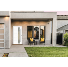 Façade de maison avec porte d''entrée moderne, fenêtres et coin salon extérieur.