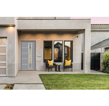 Façade de maison moderne avec porte d''entrée, fenêtres et coin salon extérieur.