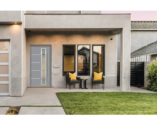 Façade de maison moderne avec porte d''entrée, fenêtres et coin salon extérieur.