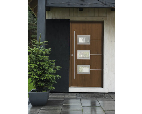 Haustür mit drei Fenstern und silberfarbenen Applikationen neben einer kleinen Tanne im Topf