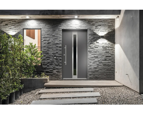 Modernes Haus mit grauer Haustür, Steinwand und gepflastertem Weg