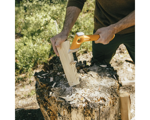 Une personne fend du bois avec une hache à fendre sur un billot.