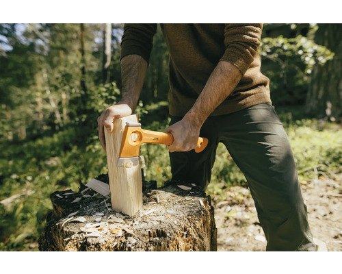 Un homme fend du bois avec une hache Fiskars sur une souche d''arbre