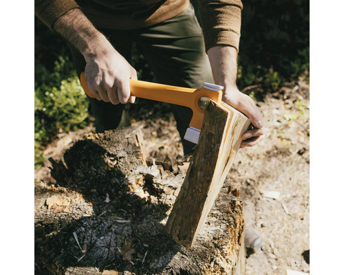 Une personne fend du bois avec une hache à fendre sur un billot.