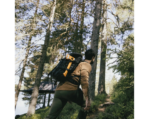 Homme avec sac à dos et hache marchant dans la forêt