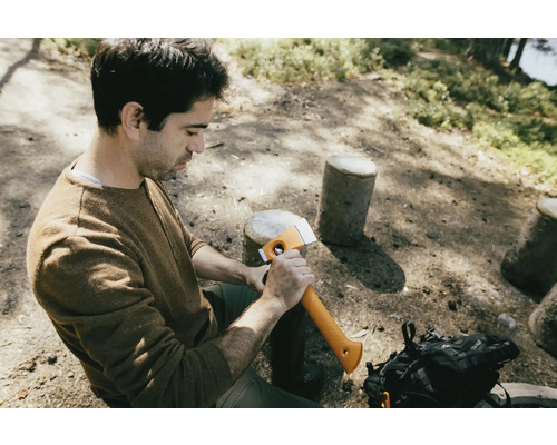 Un homme est assis dans les bois et tient une hache.