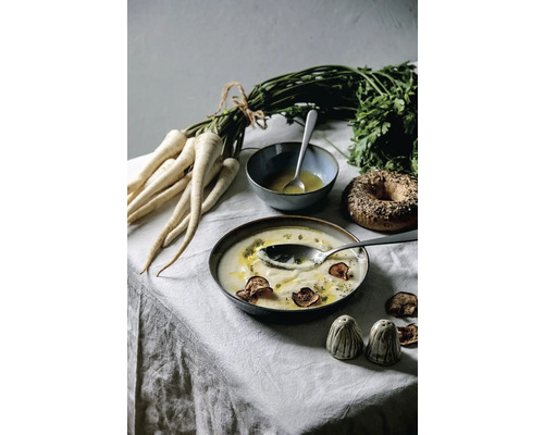 Nature morte avec soupe de panais, persil, bagel et poivrières sur une table