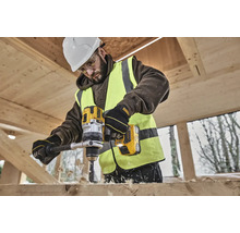 Ein Bauarbeiter bohrt mit einer gelben DeWalt Akku-Bohrmaschine ein Loch in ein Holzbrett.