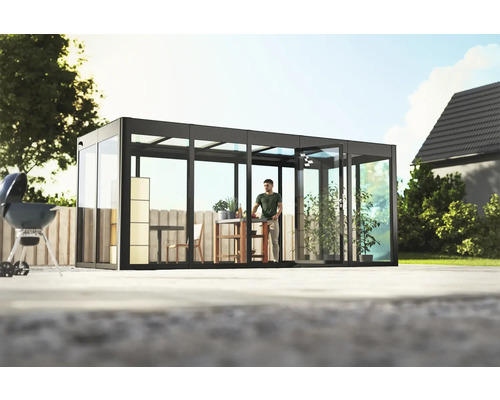 Freistehender Glasgarten mit Mann am Tisch und Grill im Freien.