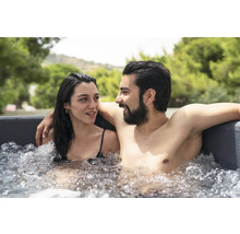 Un couple se détend dans un jacuzzi rempli d''eau à l''extérieur.