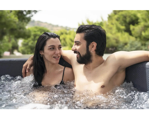 Un couple se détend dans un jacuzzi rempli d''eau à l''extérieur.