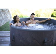 Un couple se détend dans un bain à remous gonflable à l''extérieur avec des boissons.