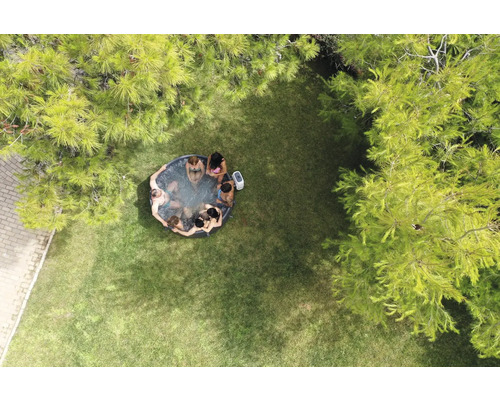 Vue aérienne d''un jardin avec un jacuzzi gonflable dans lequel plusieurs personnes sont assises.