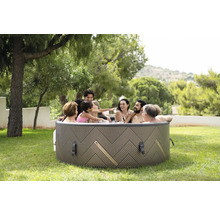Une famille se détend dans un jacuzzi gonflable dans le jardin.