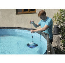 Un homme manipule un robot de piscine dans une piscine