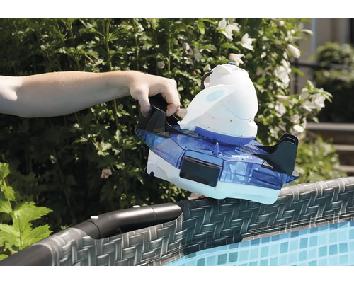 Une main place un nettoyeur de piscine sur le bord d''une piscine.