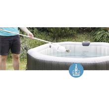 Une personne nettoie un bain à remous gonflable avec un aspirateur