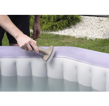 Une personne nettoie une piscine gonflable avec une brosse.