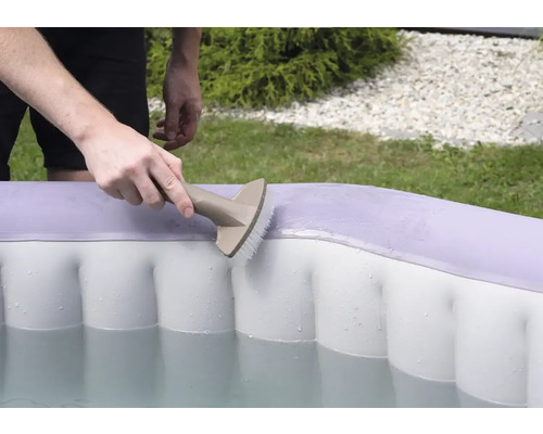 Une personne nettoie une piscine gonflable avec une brosse.