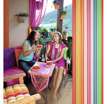 Zwei Frauen trinken Kaffee auf einem Balkon mit farbenfroher Dekoration und einem Lamellenvorhang.