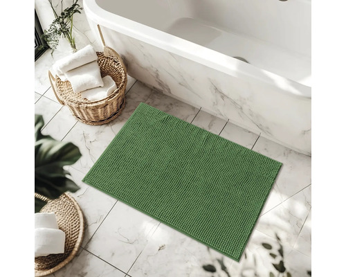 Tapis de bain vert dans la salle de bain à côté de la baignoire et des paniers avec des serviettes
