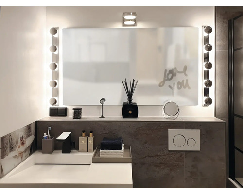 Badezimmer mit Spiegel, Beleuchtung, Waschbecken und Accessoires für ein helles Ambiente